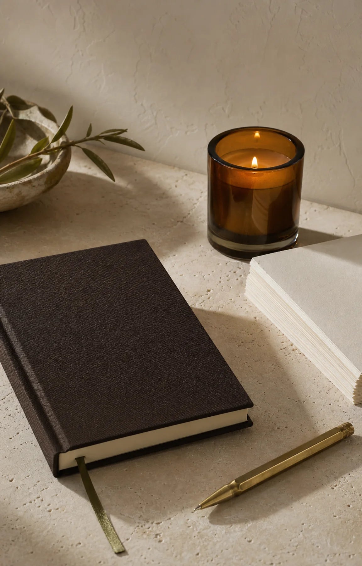 A linen journal, brass pen, candle, and notecards