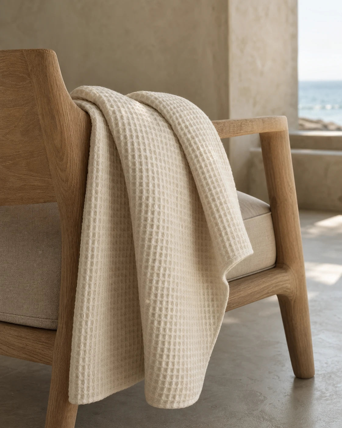 Warm ivory waffle-weave linen throw draped over a pale oak chair